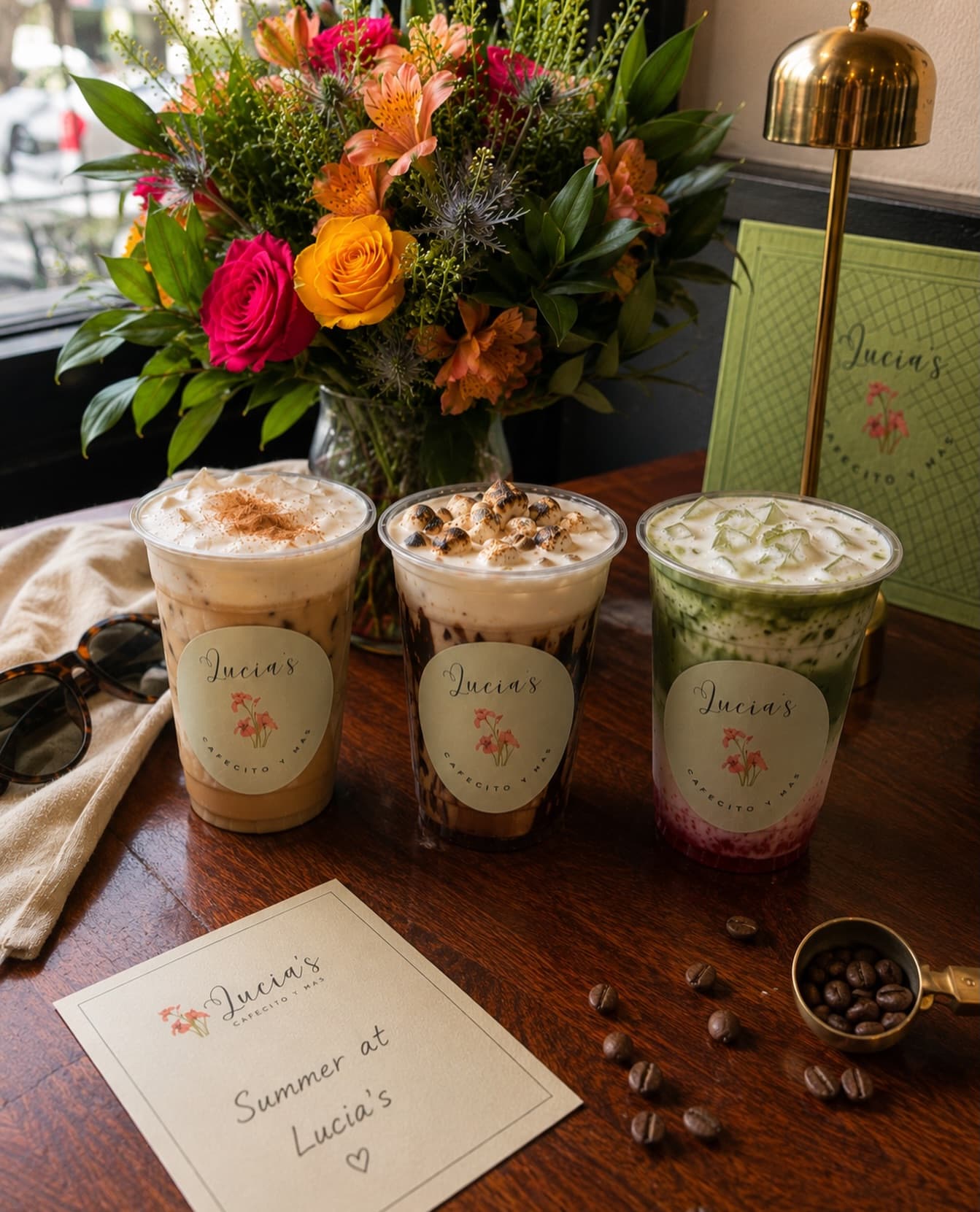 Iced Lucia’s drinks in branded cups beside a bright bouquet of flowers