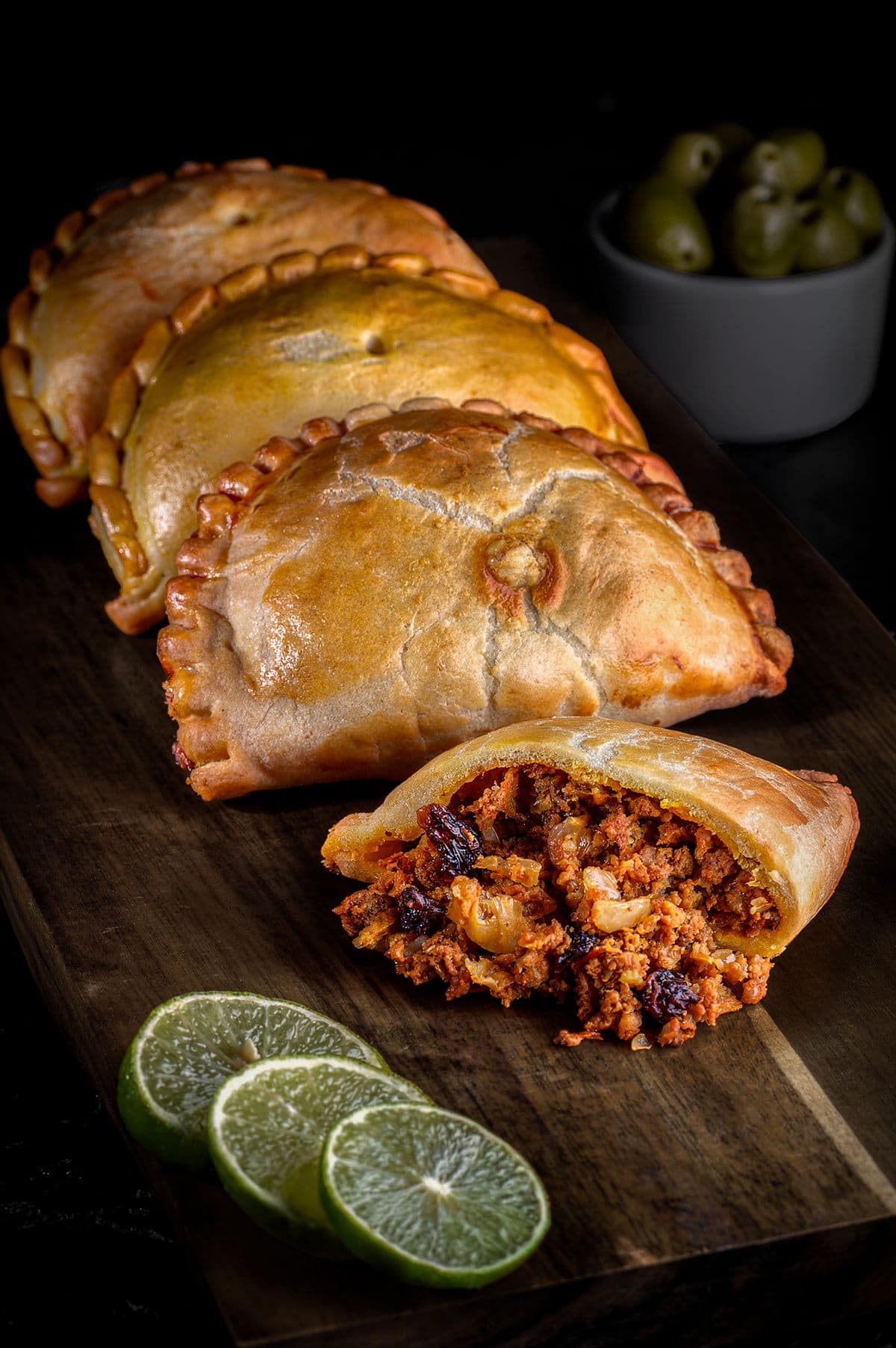 A golden beef empanada cut open to show the seasoned filling