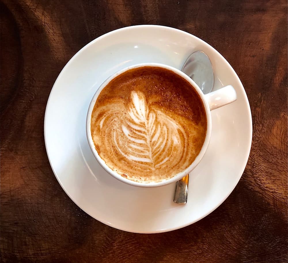 A Spanish latte in a clear glass on a cream counter at Lucia's